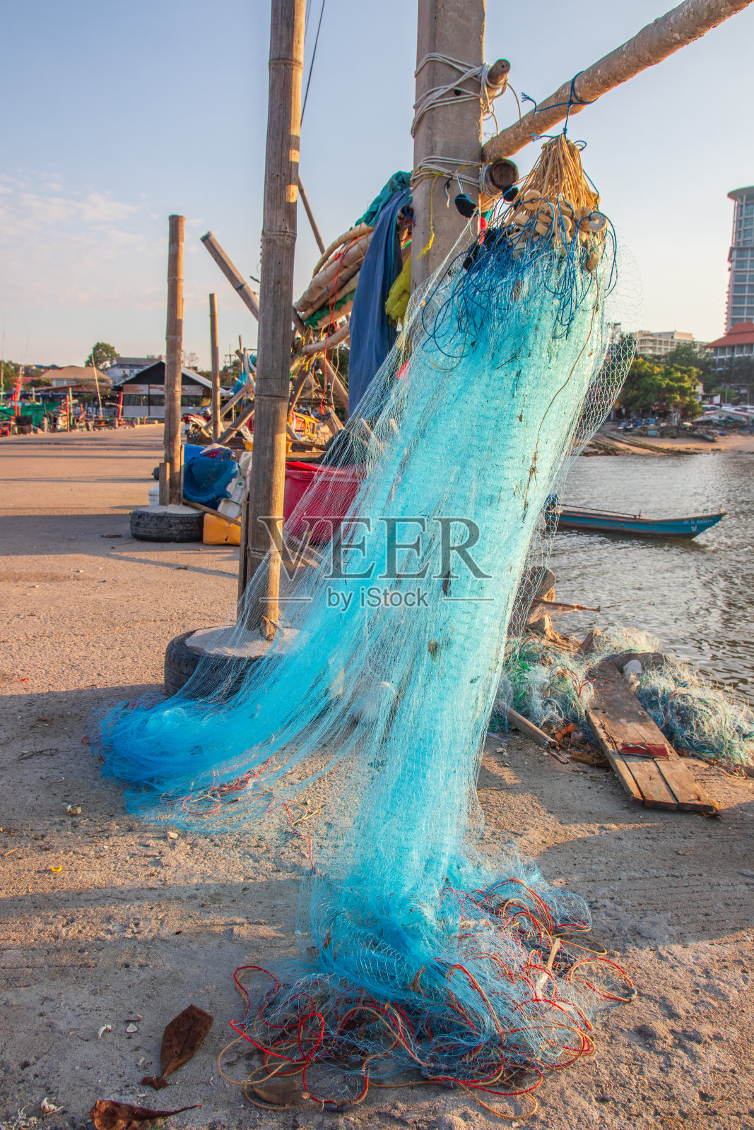 捕到鱼后，直接在码头上维护渔网，布置并挂在一根杆子上照片摄影图片