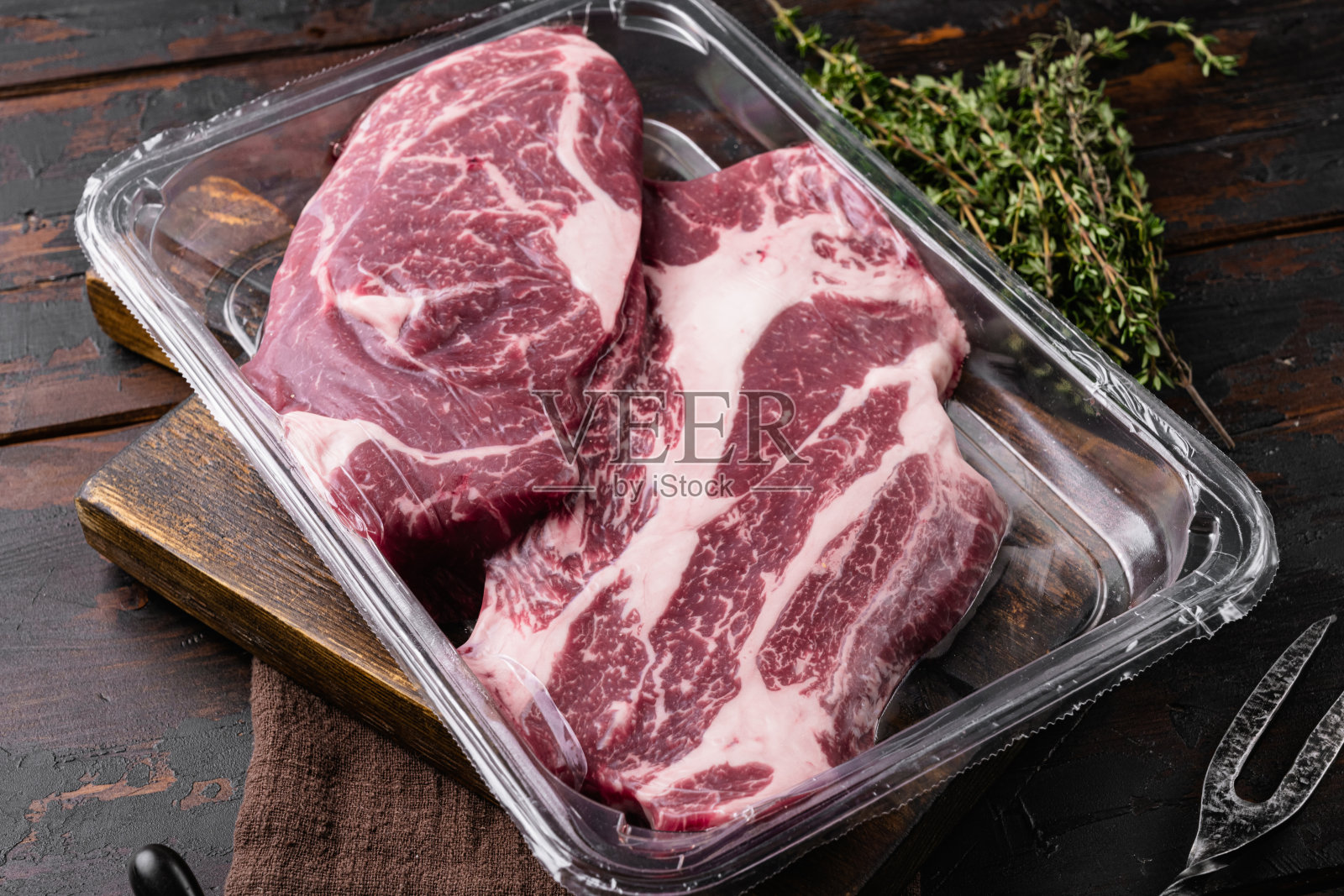 真空包装的有机生牛排查克眼圈，在旧的深色木制桌子的背景照片摄影图片