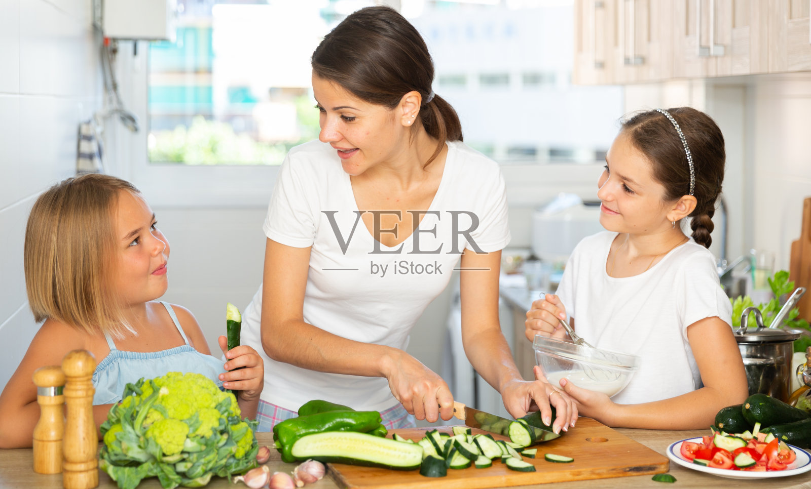 一个年轻的女人和两个女儿一起做饭照片摄影图片