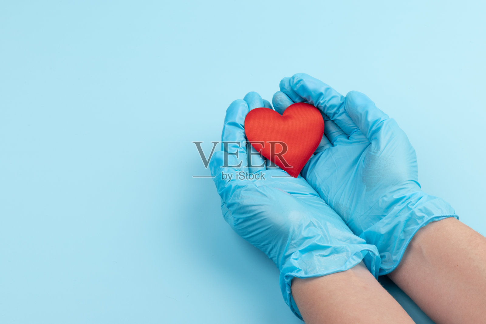 红色的心在手上，蓝色的医用手套在蓝色的背景上。背景为一天的医疗，顶视图，文本空间照片摄影图片