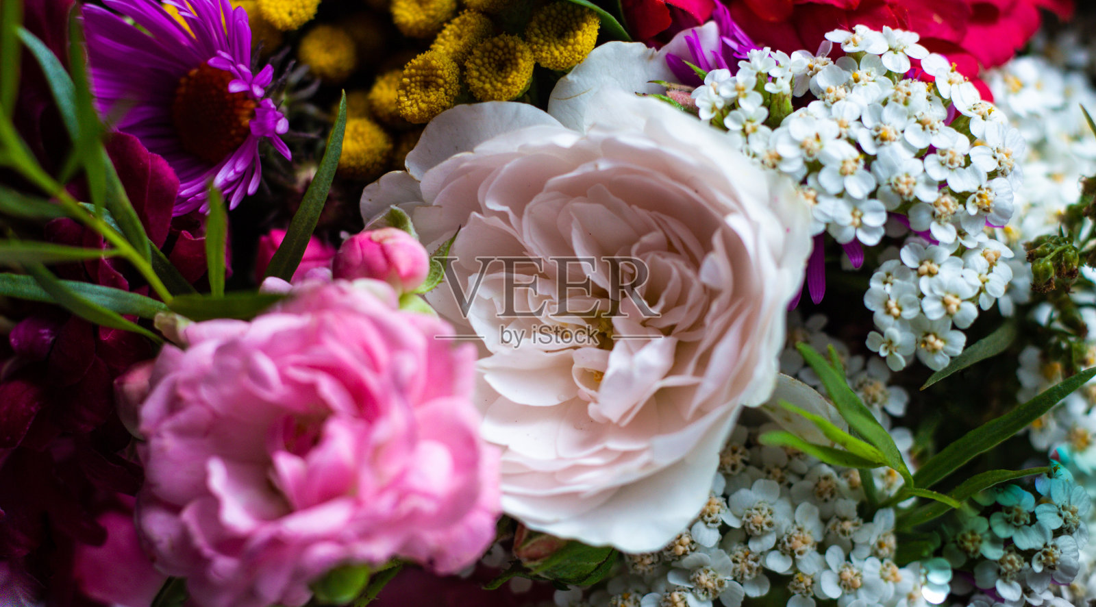 不同的花在花束的特写背景。粉红色、黄色、紫色和白色的鲜花照片摄影图片