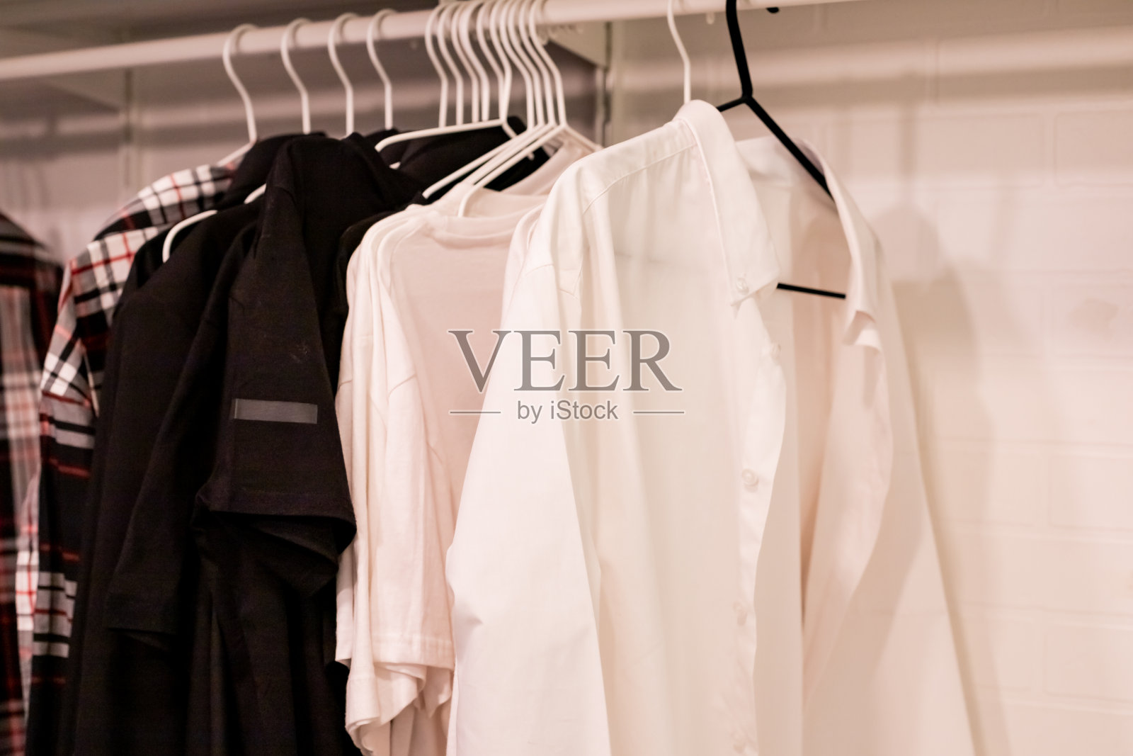 衣柜衣柜里不同衣服的衣架。衬衫和衣服挂在家里木制衣柜的栏杆上。服装精品店照片摄影图片