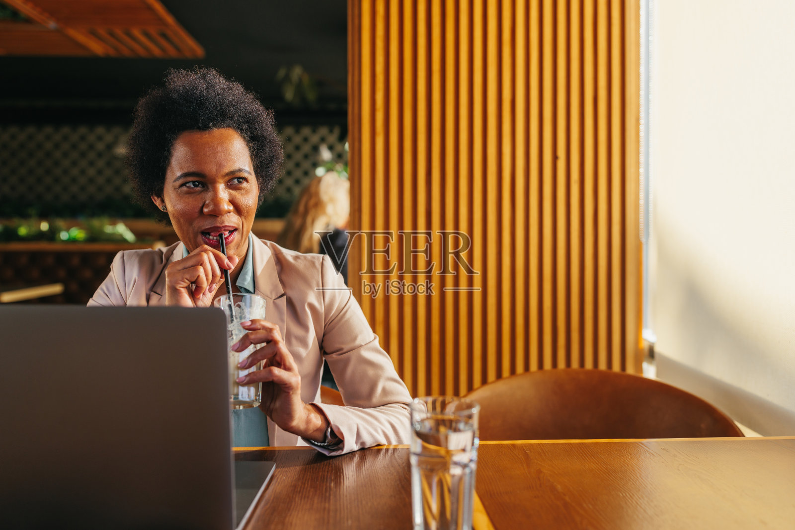 非洲裔女商人坐在咖啡馆，喝饮料和工作照片摄影图片