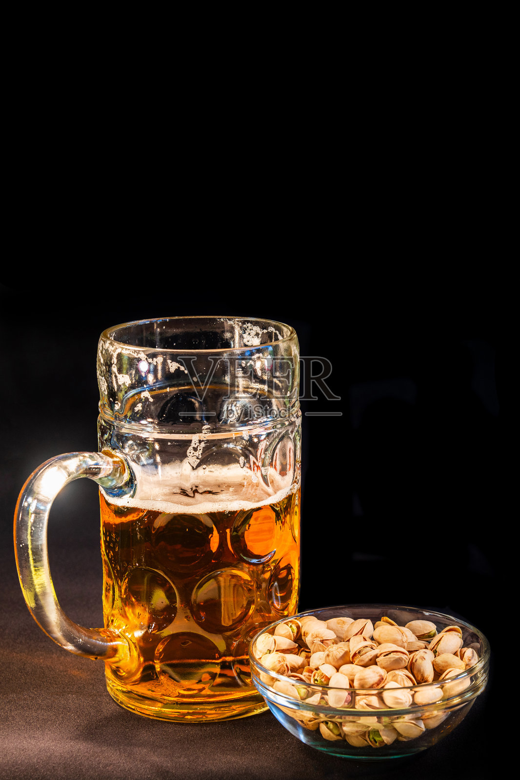 封面页传统的十月巴伐利亚啤酒在一个大的一升杯半喝湿的墙壁和开心果，德国，在黑色背景与文本的拷贝空间。照片摄影图片