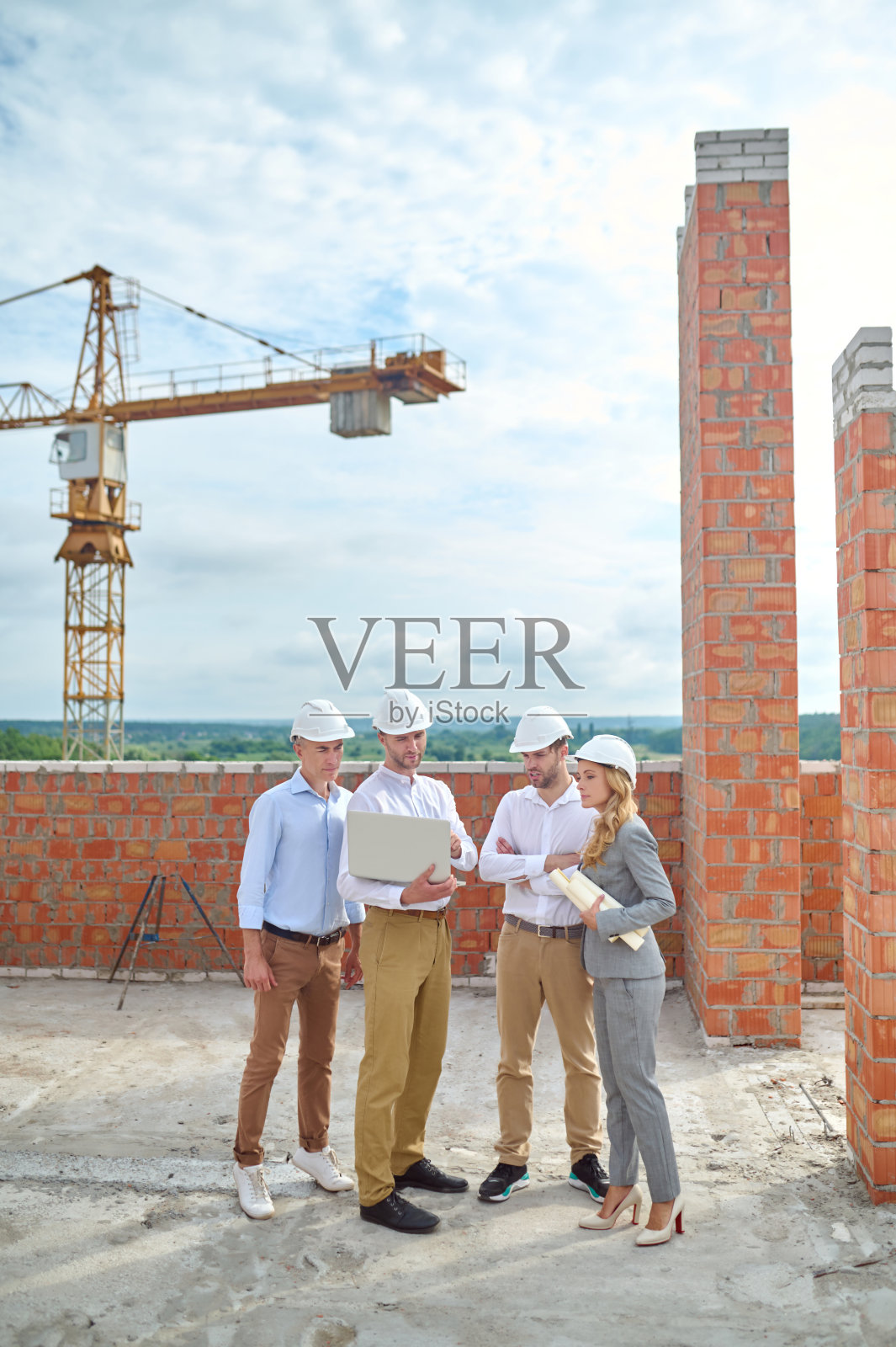 在户外，年轻的建筑工程师聚精会神，周围都是他的同事照片摄影图片