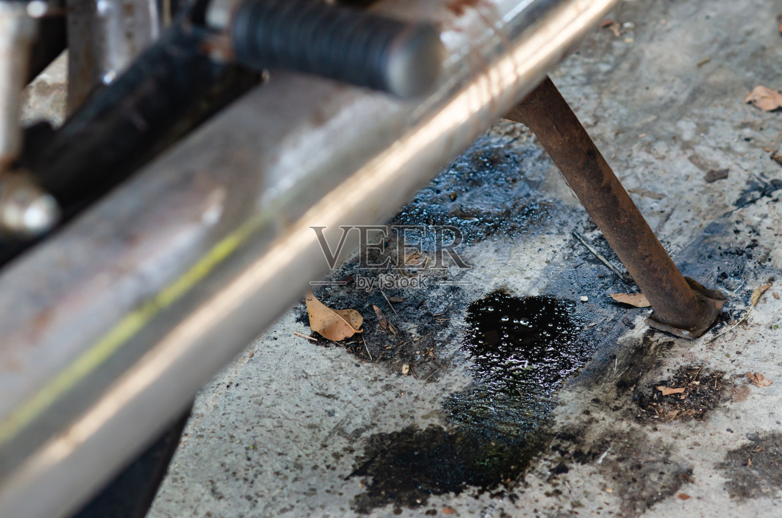 一辆旧摩托车，机油漏到了地上。照片摄影图片