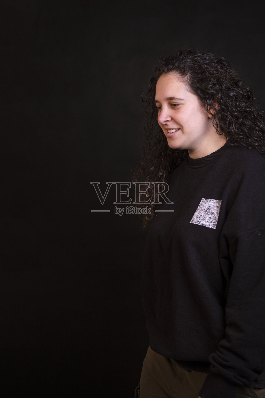 白人女孩与卷曲的头发在黑色的背景。照片摄影图片