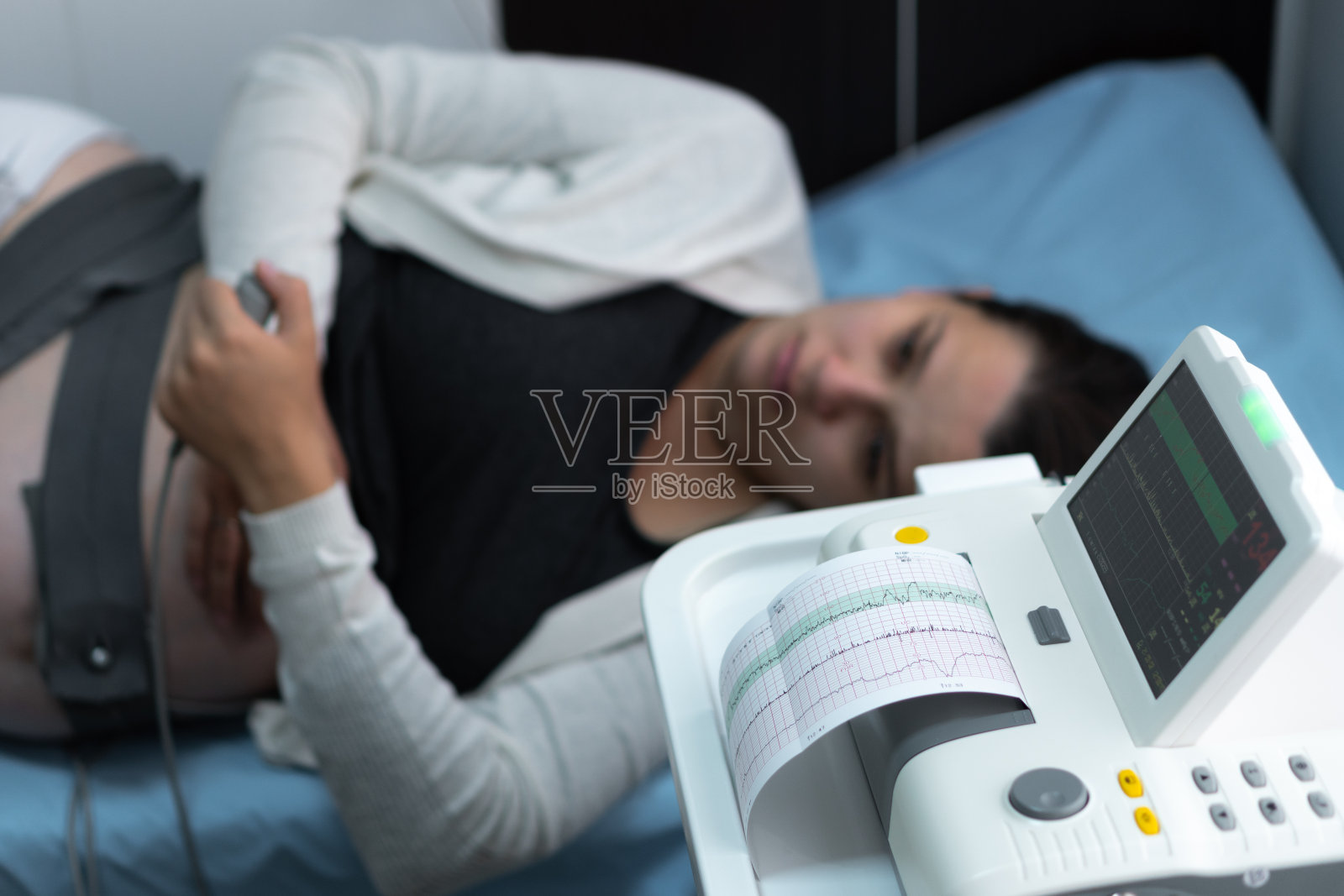 孕妇在医院的沙发上进行医疗控制心脏造影。妇科医生手打开调节CTG装置临床顾问。检查孕妇腹部健康检查照片摄影图片