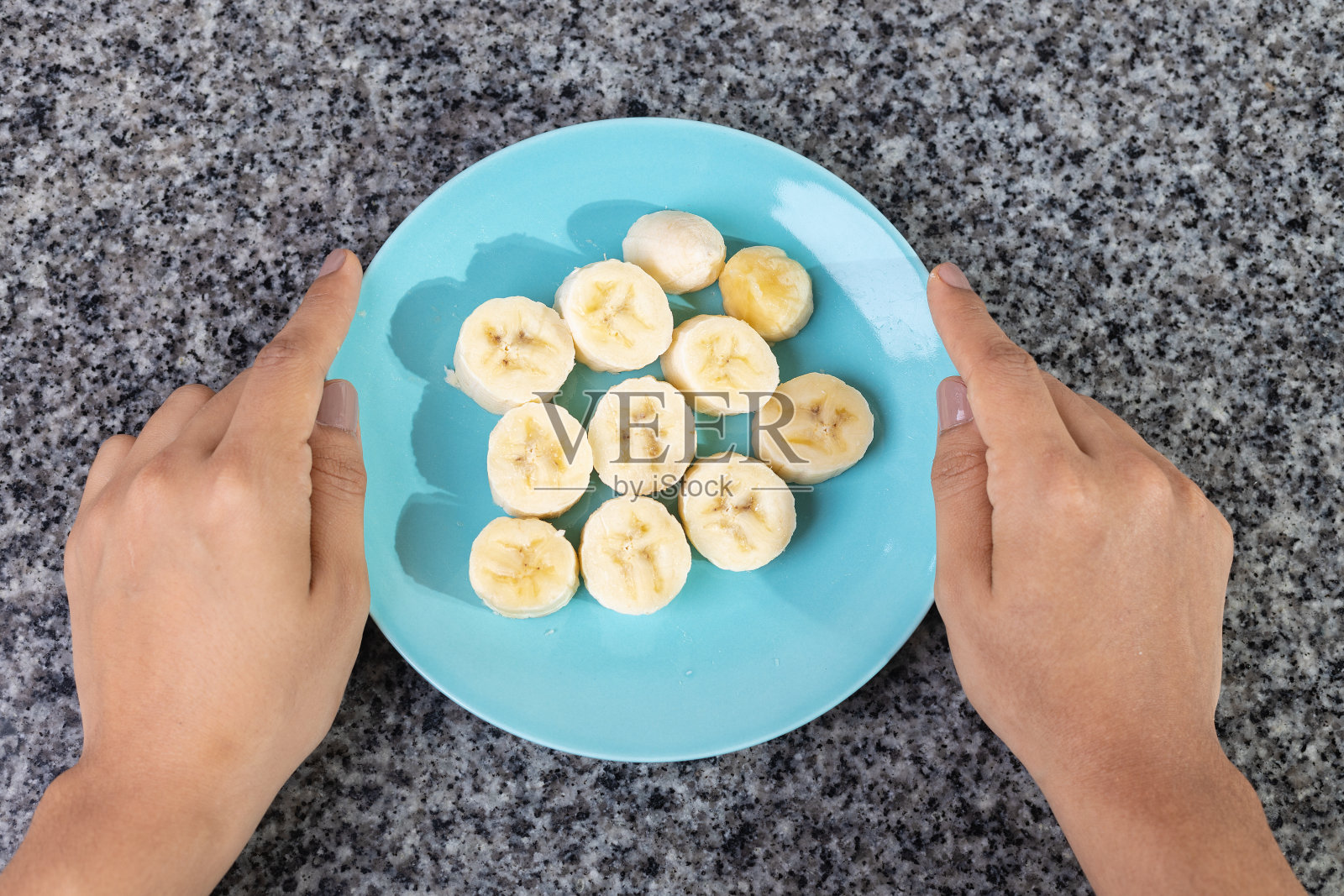在厨房里，手拿着放着香蕉片的浅蓝色盘子照片摄影图片