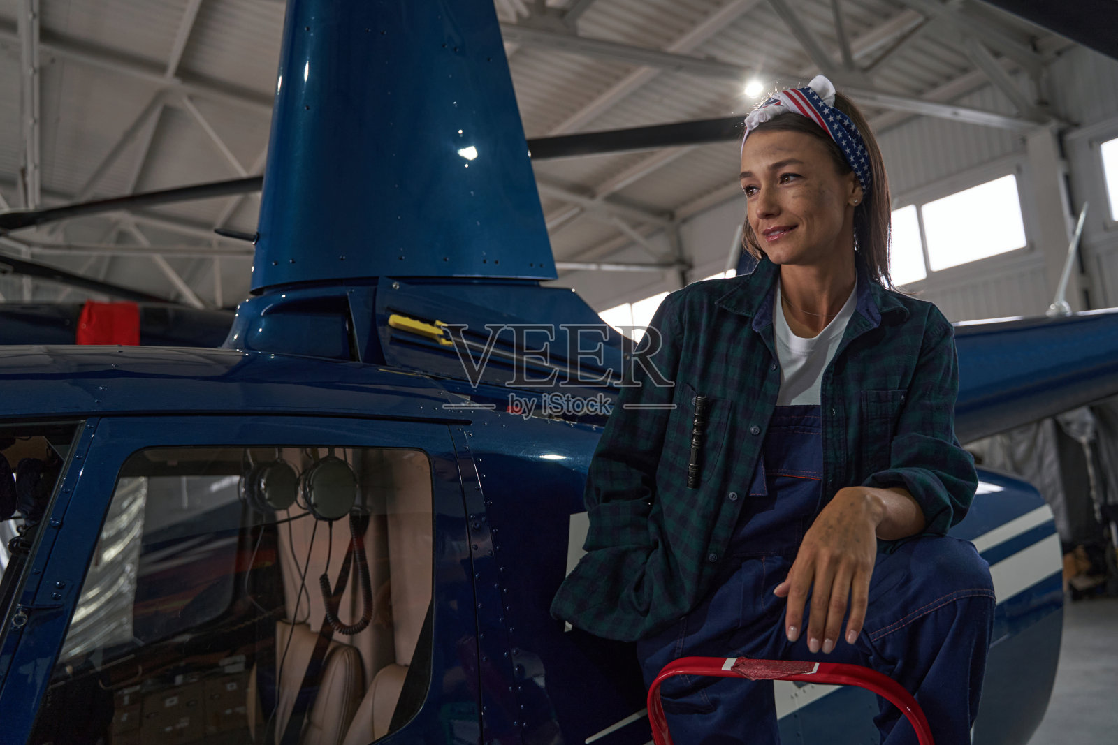 迷人优雅的女机械师在机库的直升机旁摆姿势拍照照片摄影图片
