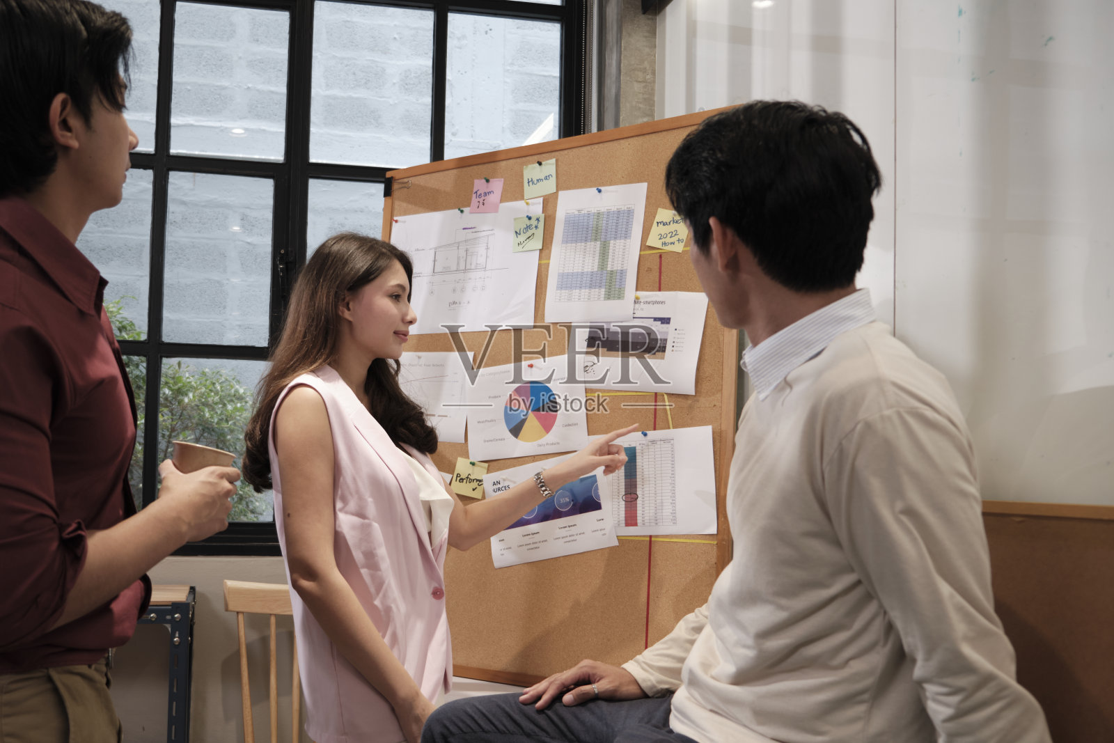 女员工向商务办公室的亚洲同事介绍财务策略。照片摄影图片