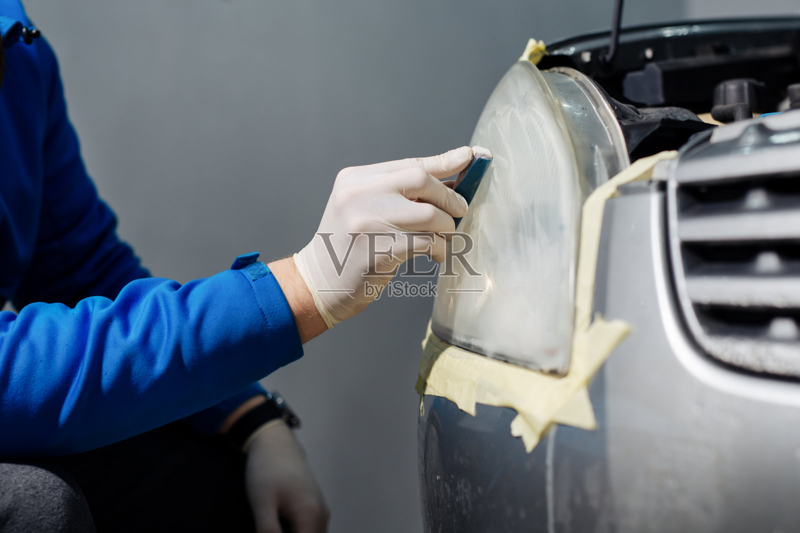 工人用电动工具打磨汽车前灯的光学镜片。照片摄影图片