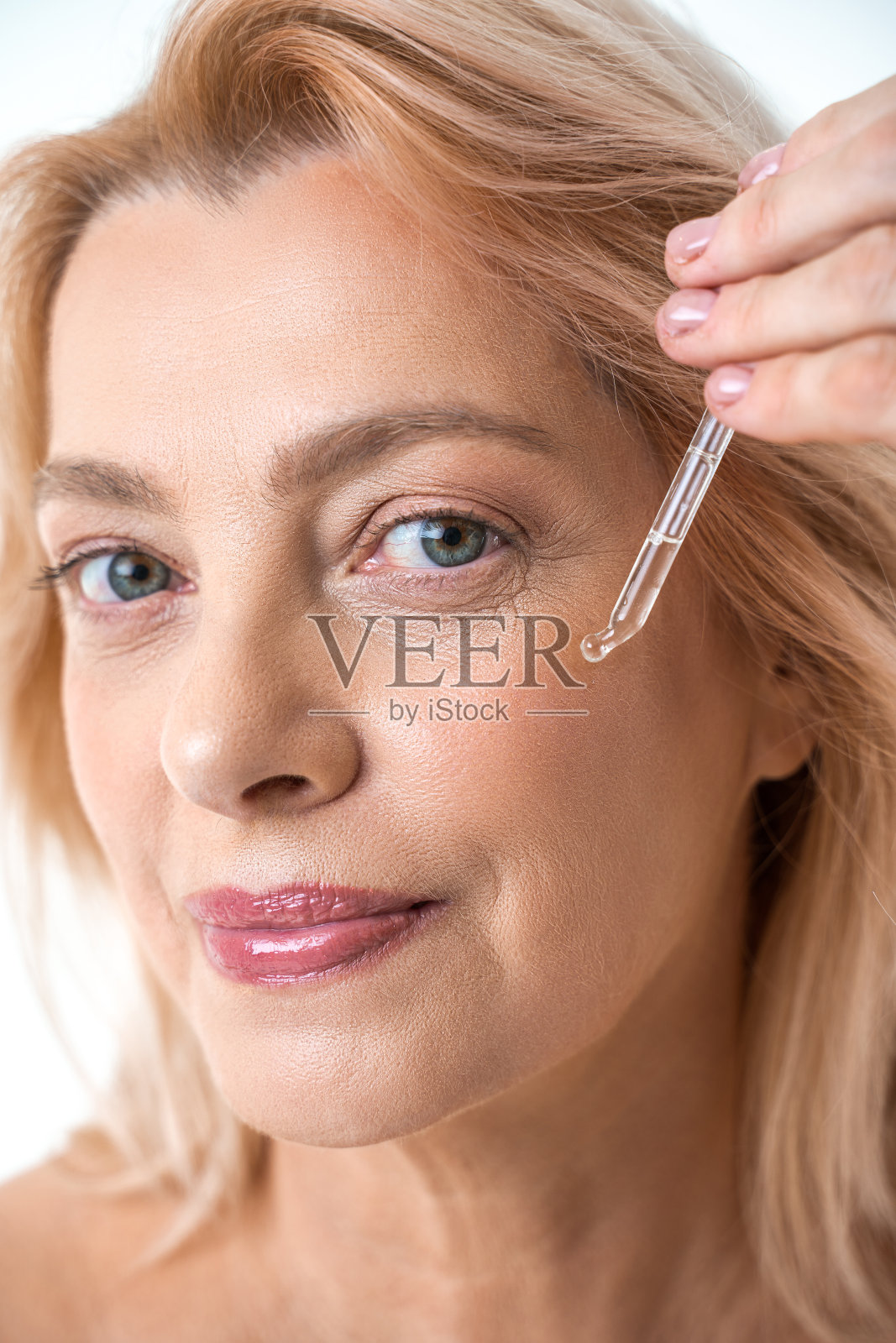 成熟女人用吸液管吸油精华液的肖像照片摄影图片