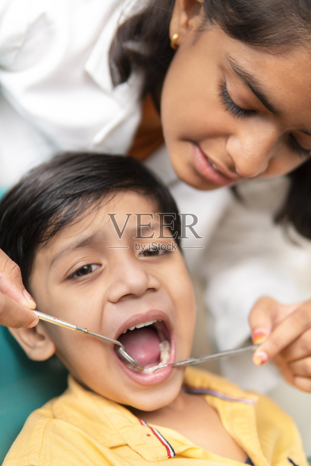 快乐的女牙医助理在诊所检查小男孩的牙齿。照片摄影图片