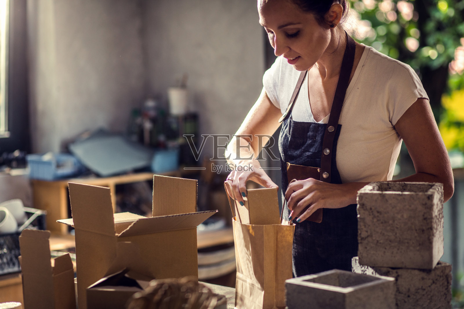 在她的车间里工作的手工艺人正在包装用于运输的装饰混凝土花瓶。照片摄影图片