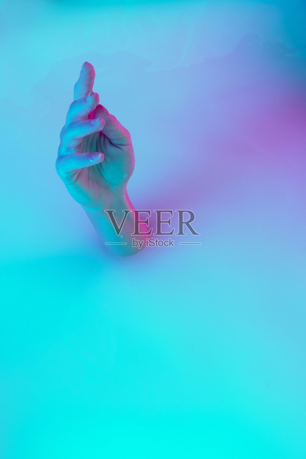 近距离的女性手势从牛奶浴与柔和的白色发光霓虹灯。广告、销售、美容、时尚风格理念。照片摄影图片