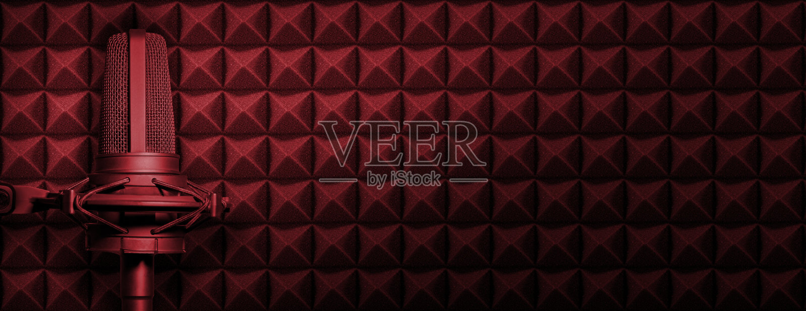 暗红色播客或录音工作室背景与声学泡沫和黑色麦克风。带有复制空间的音频横幅。照片摄影图片