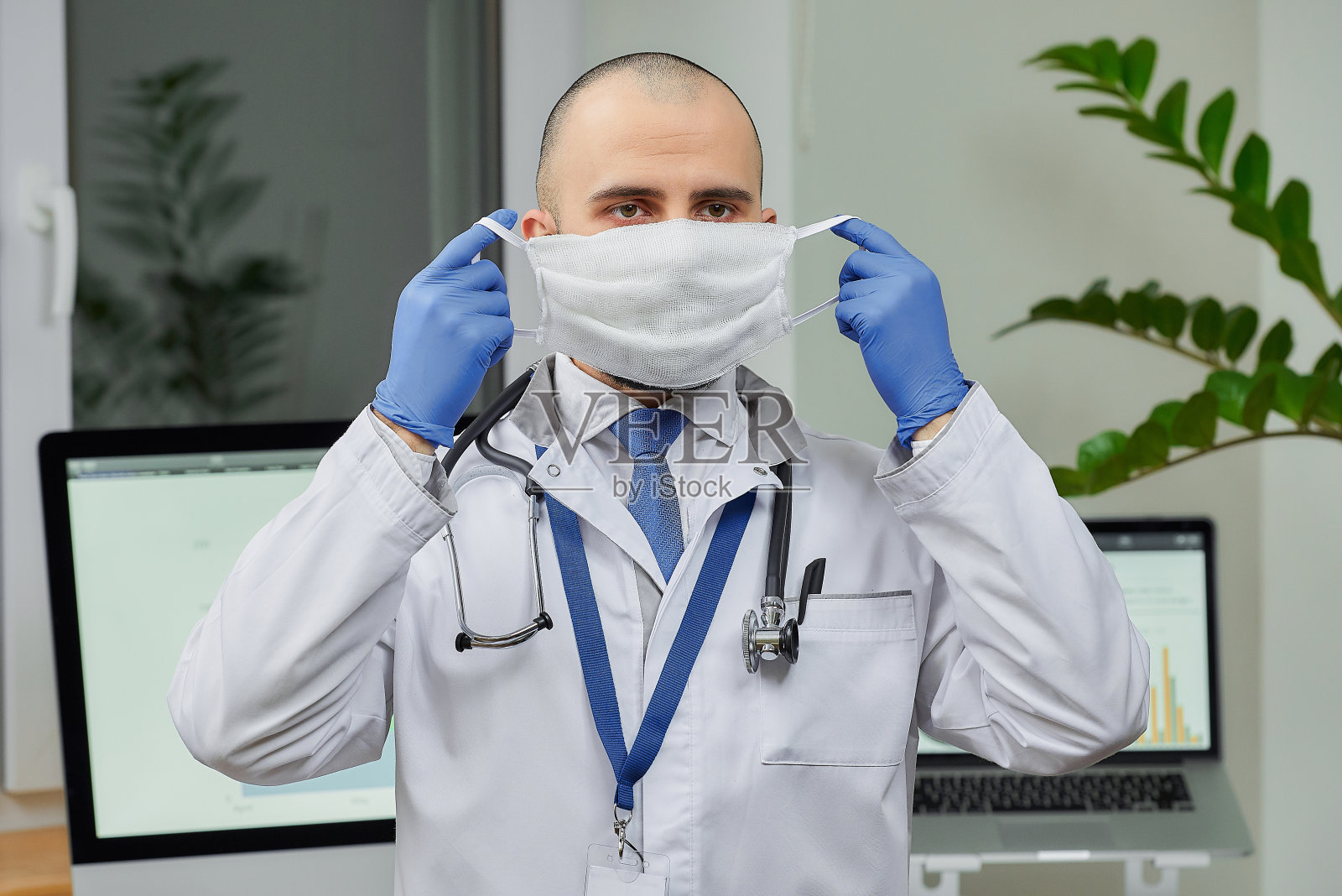 一名白人医生戴上防护口罩检查病人。照片摄影图片