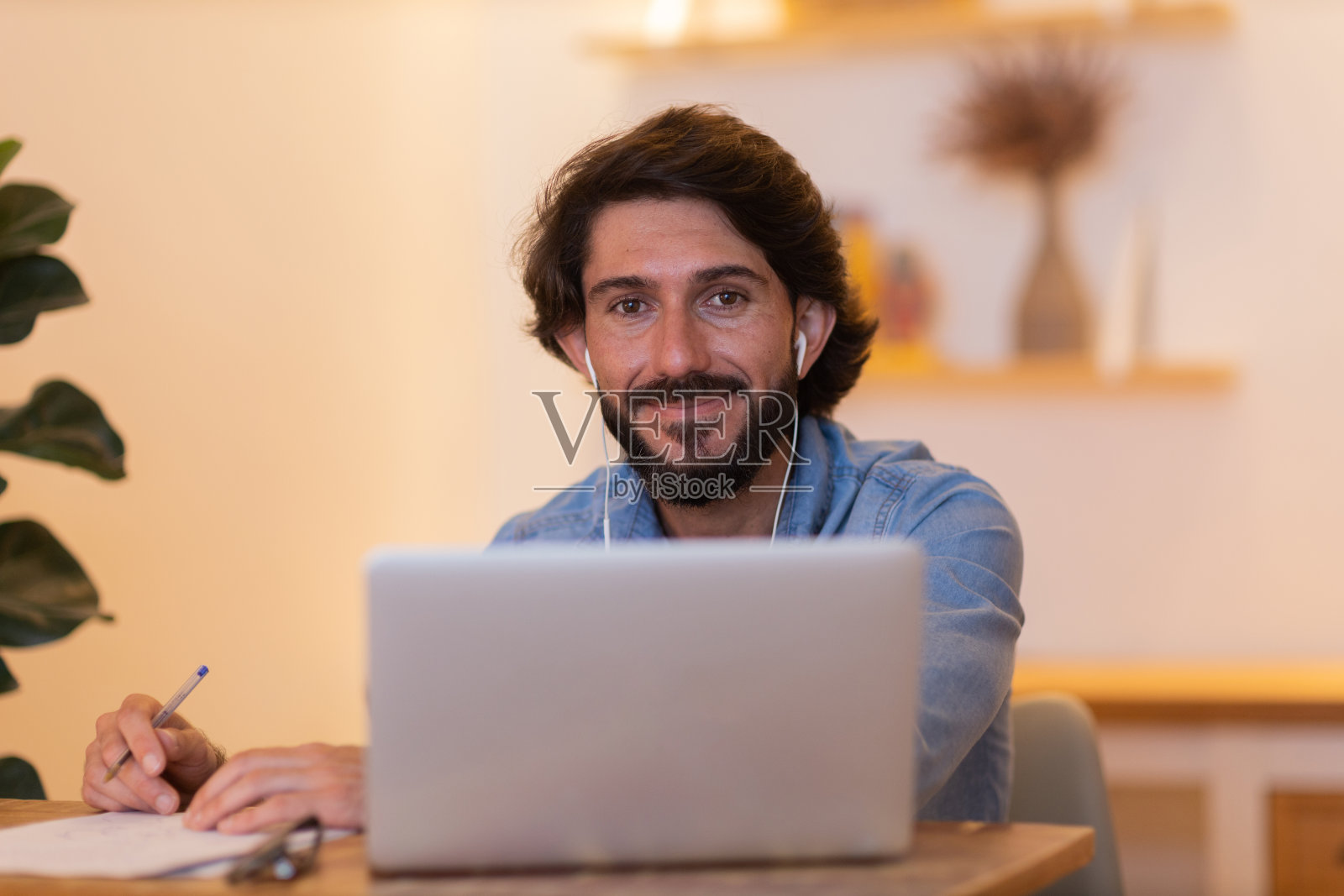 年轻的商人在家里工作，笔记本电脑和桌子上的文件。家庭办公室的概念。照片摄影图片