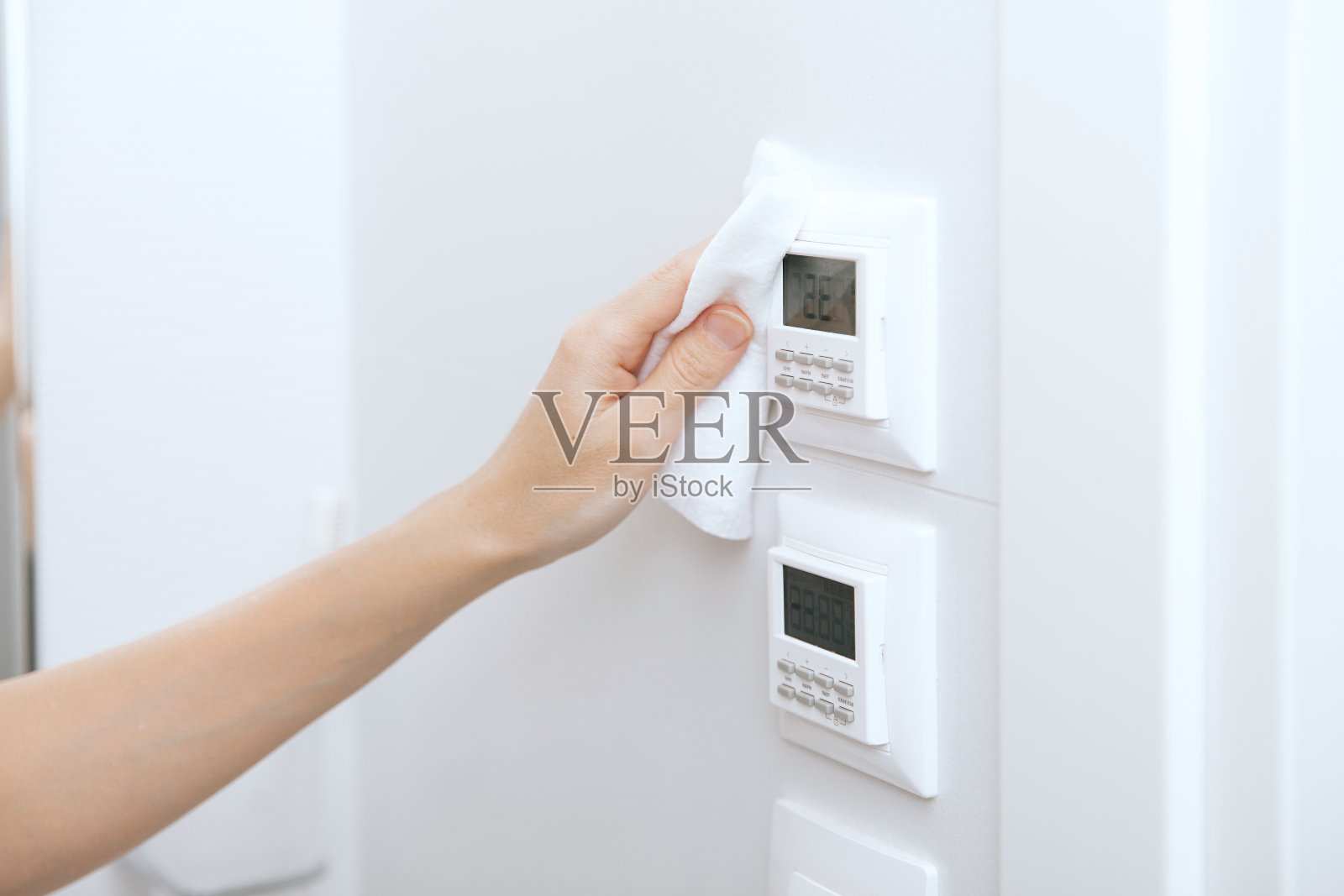 用超细纤维布清洁开关和插座。妇女用湿纸巾擦拭家用房门连接。消毒医院和公共场所的表面，防止冠状病毒感染照片摄影图片