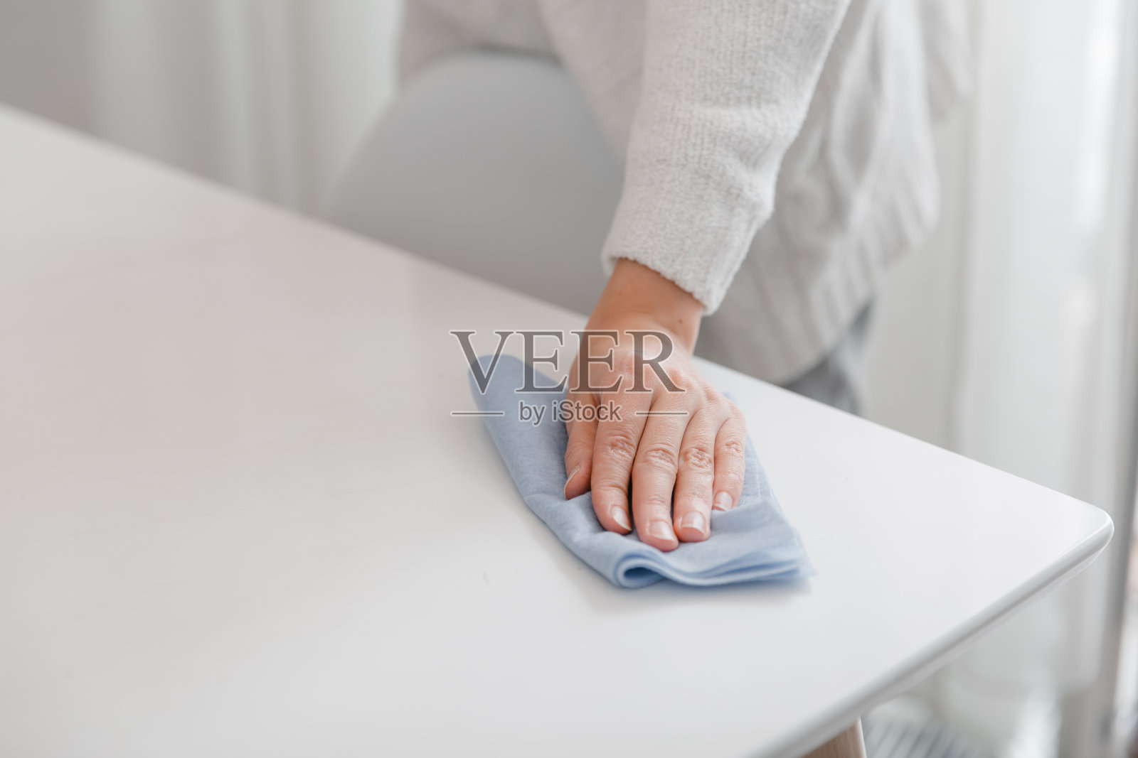 用蓝色超细纤维布清洁桌子。消毒医院和公共场所的表面，防止冠状病毒感染。女人在家用湿纸巾擦手。打扫房间照片摄影图片