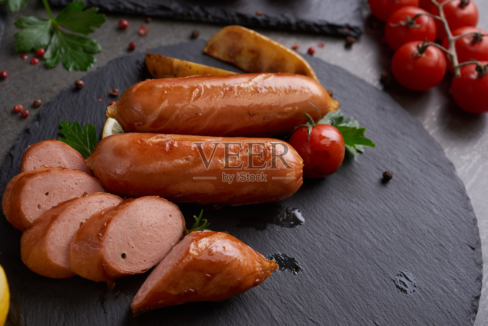 香肠和烹饪材料。烤香肠加入香草和香料，蔬菜，迷迭香，百里香放在烤盘上，烧烤食物，烧烤，烧烤，在石桌上。前视图。照片摄影图片