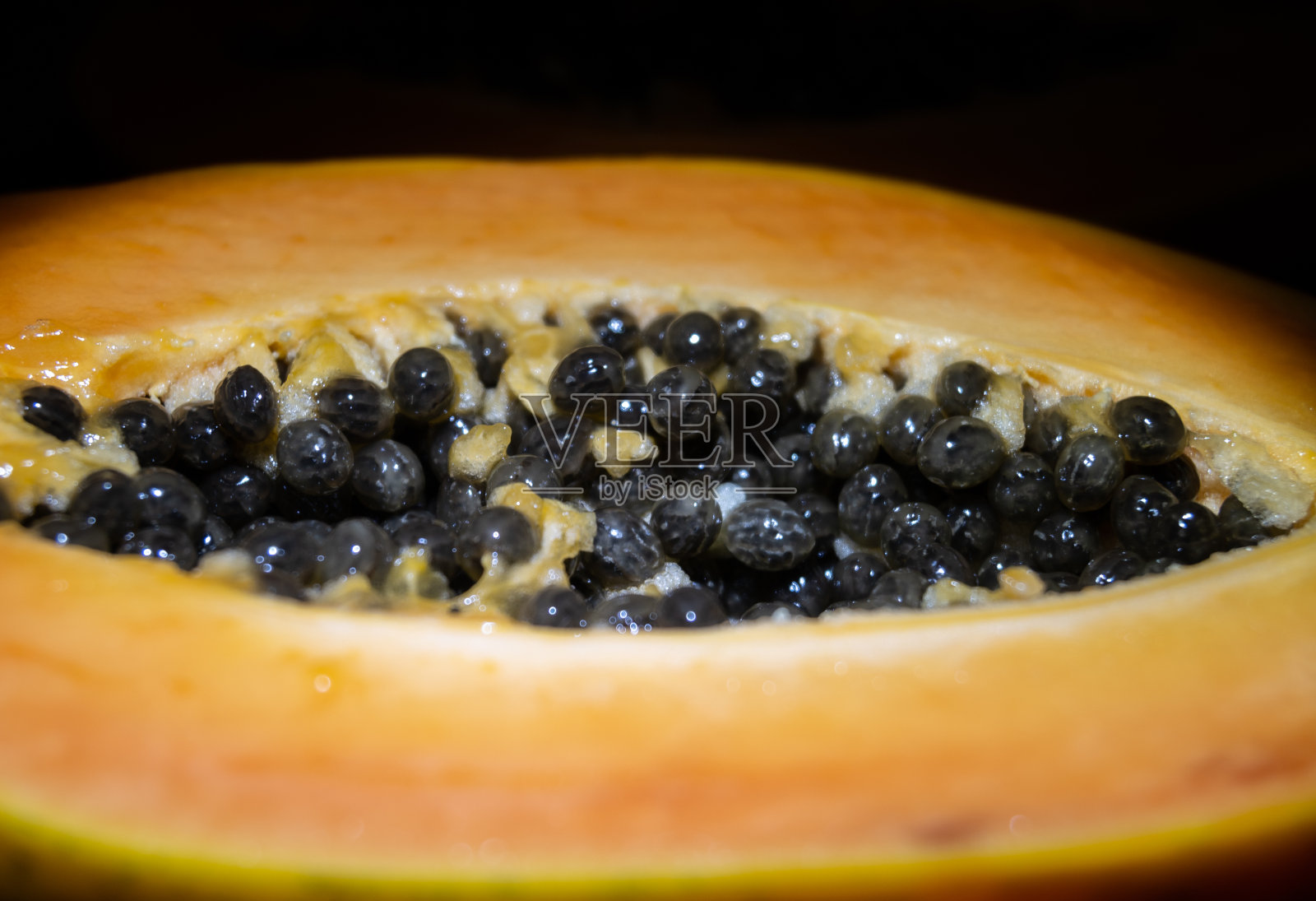 在木制背景上切成两半的木瓜。照片摄影图片