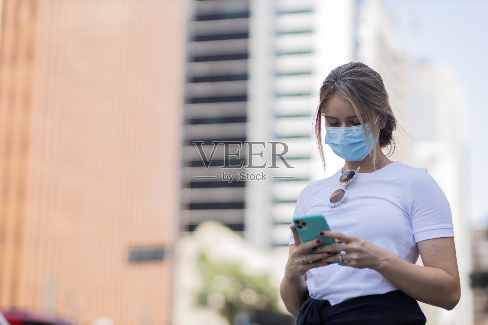 年轻人在白天使用智能手机的视图，背景是城市景观。高质量的照片照片摄影图片