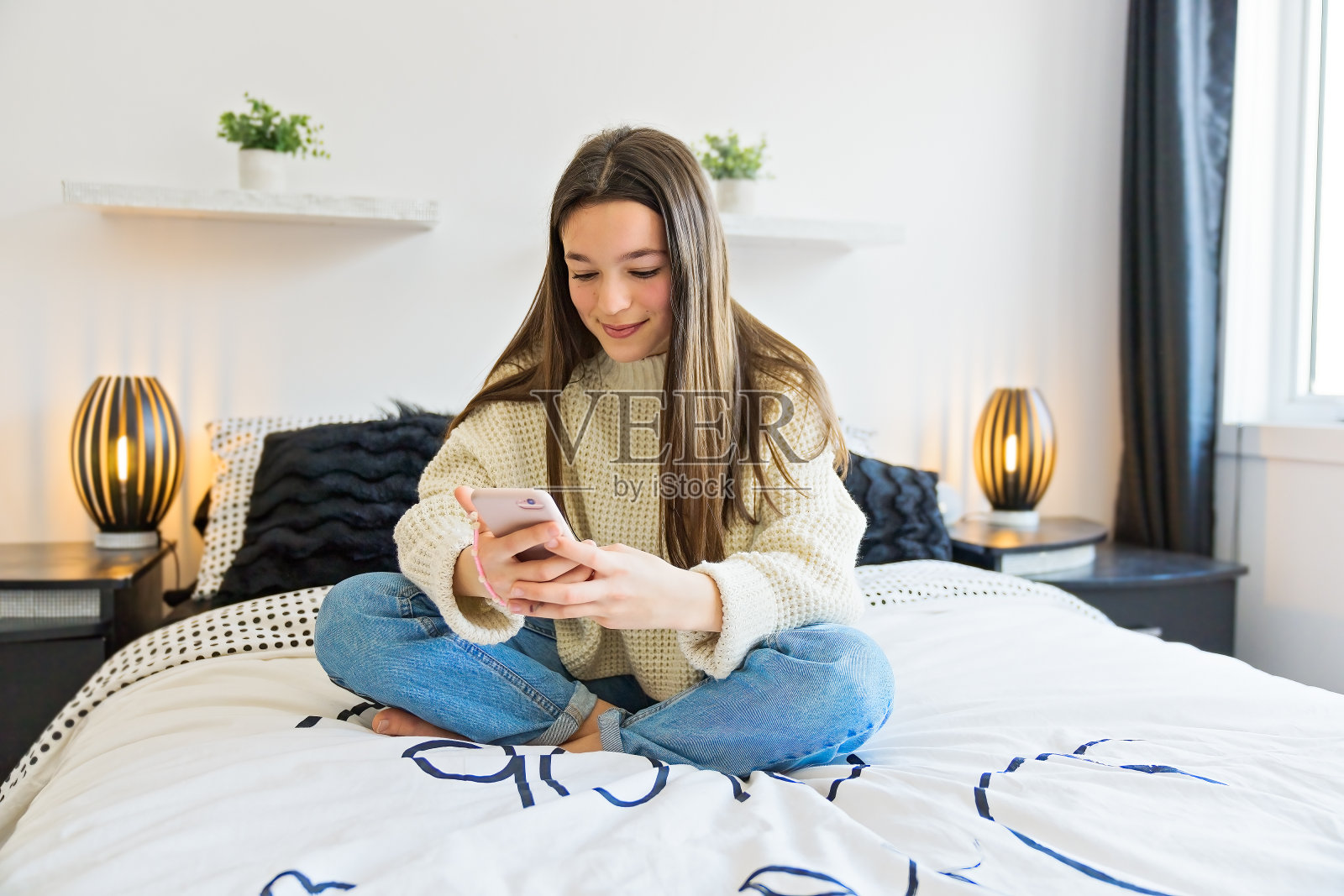 一个十几岁的女孩把智能手机放在床上照片摄影图片