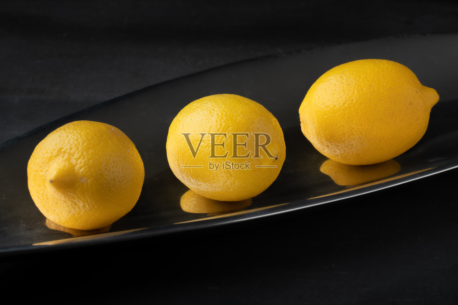 三个新鲜的柠檬放在反光的表面照片摄影图片