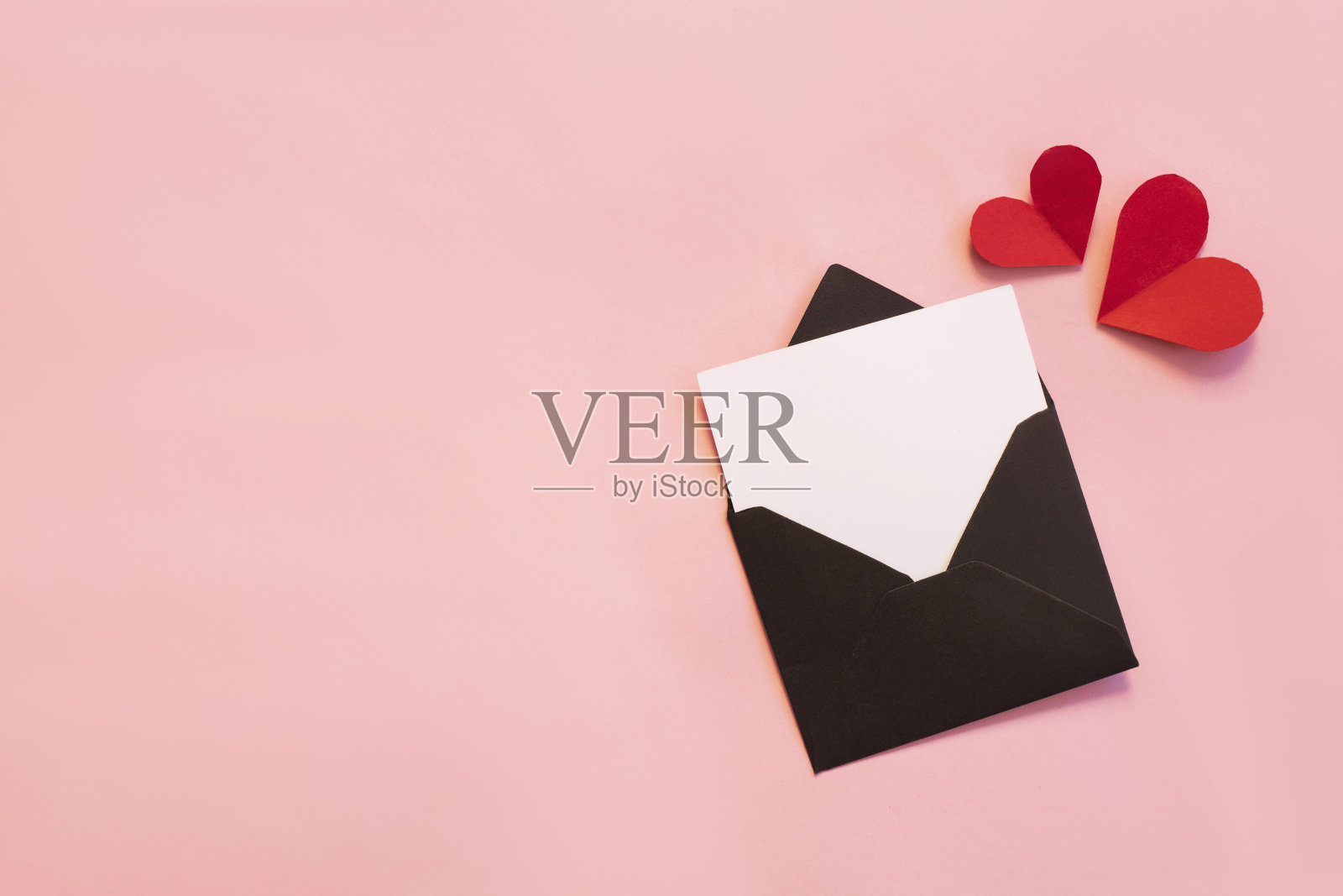 黑色的纸信封空白白色的笔记模型里面和情人节的心在粉红色的背景。平躺，俯视图。浪漫的情书情人节的概念照片摄影图片