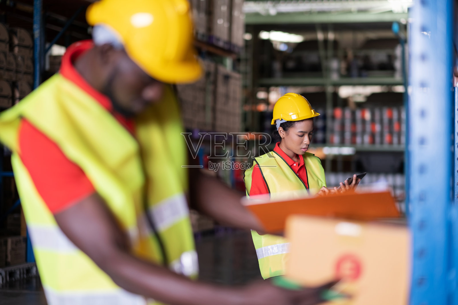 非裔美籍工程师妇女，头戴安全帽，身穿背心，手持平板，站在汽车零件仓库里。检查货物库存。工人的画像。物流和经营理念照片摄影图片