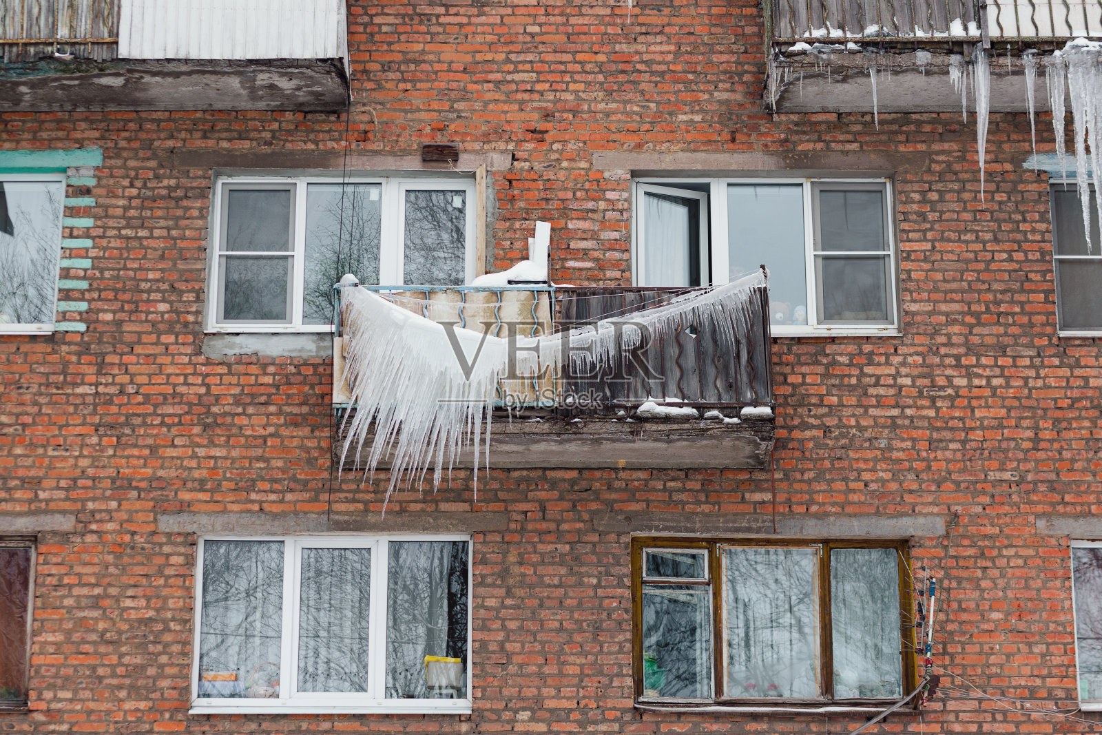 俄罗斯。由于糟糕的屋顶风暴系统，多层建筑的阳台上形成了可怕的巨大冰柱照片摄影图片