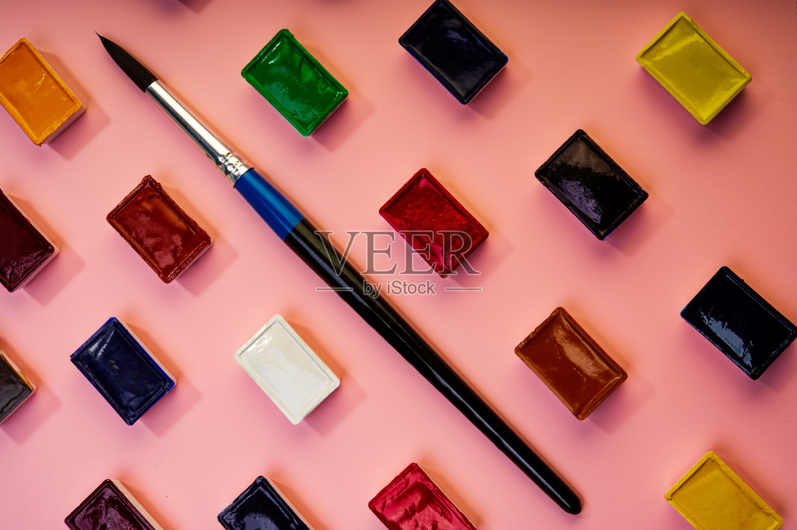 艺术画笔和水彩颜料躺在粉红色的背景上。照片摄影图片