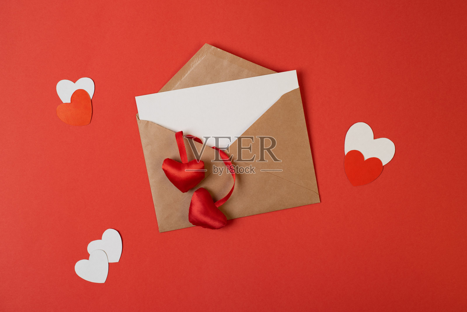 手工信封空白白色的笔记模型内和情人节的心在红色的背景与红色和白色的心。照片摄影图片