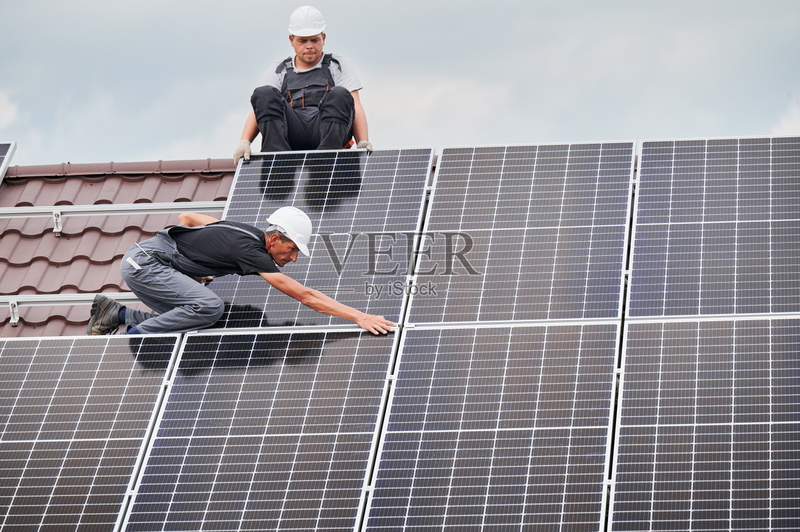 工人在屋顶安装太阳能电池板。照片摄影图片