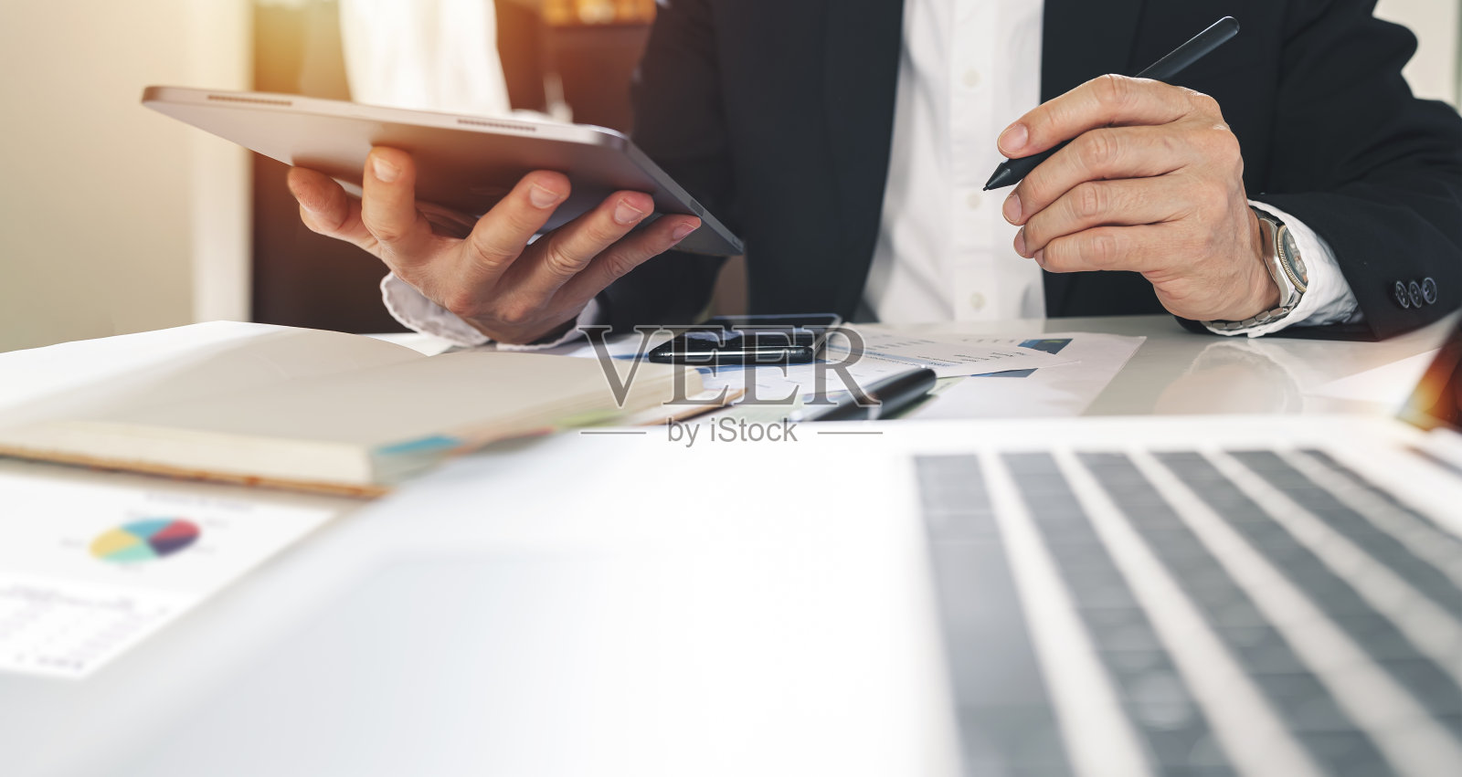 商人使用数字平板电脑工作分析商业信息，计划分析投资和营销，而坐在办公桌前。照片摄影图片