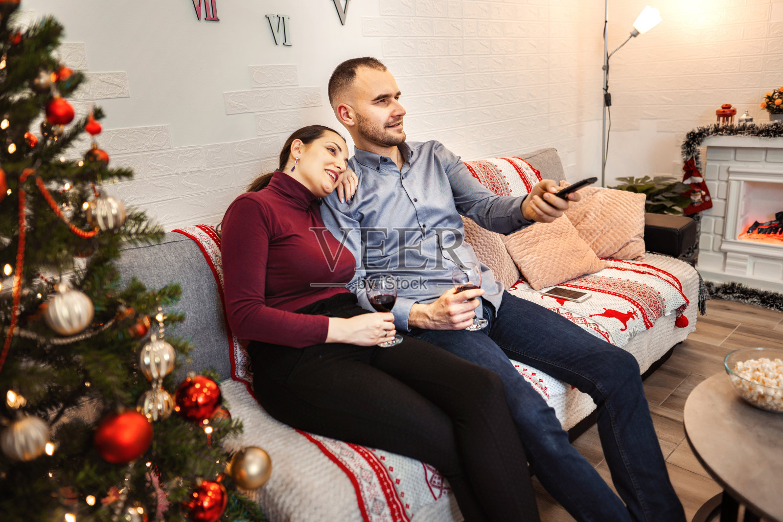年轻幸福的夫妇在圣诞节看电视和喝葡萄酒照片摄影图片