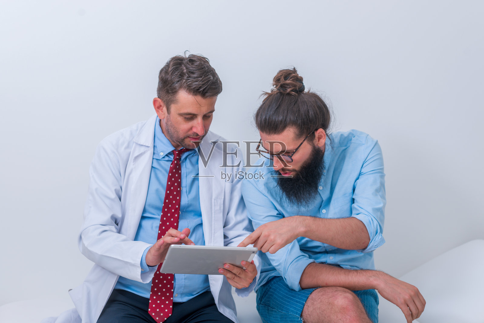 一位医生正在办公室里和一位时髦的病人交谈，并向他解释他的诊断。照片摄影图片