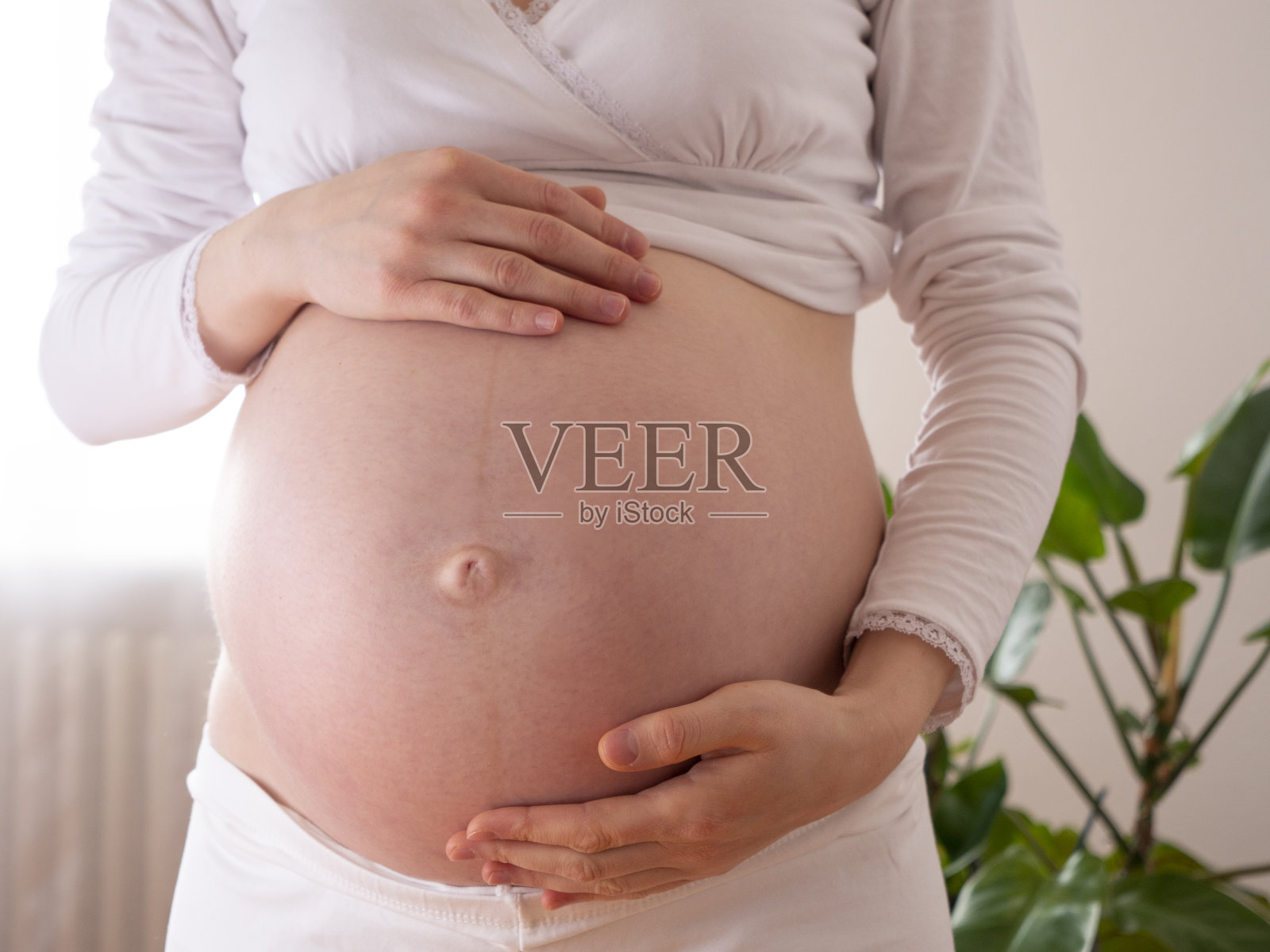 正面看孕妇触摸她裸露的腹部抚摸她的皮肤，皮肤和身体护理照片摄影图片