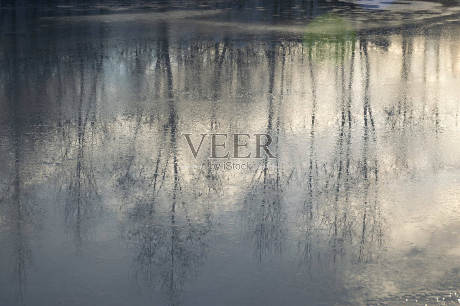 抽象而模糊的树映在湖面上，溶化的湖水，美丽的纹理，美丽的冬季湖水景观照片摄影图片