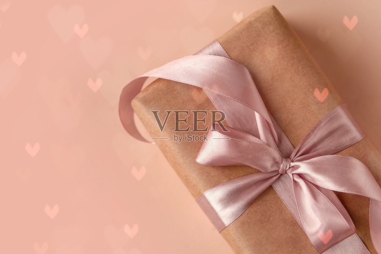 情人节，生日或新年礼物在牛皮纸粉红色丝带软米色背景与闪光照片摄影图片