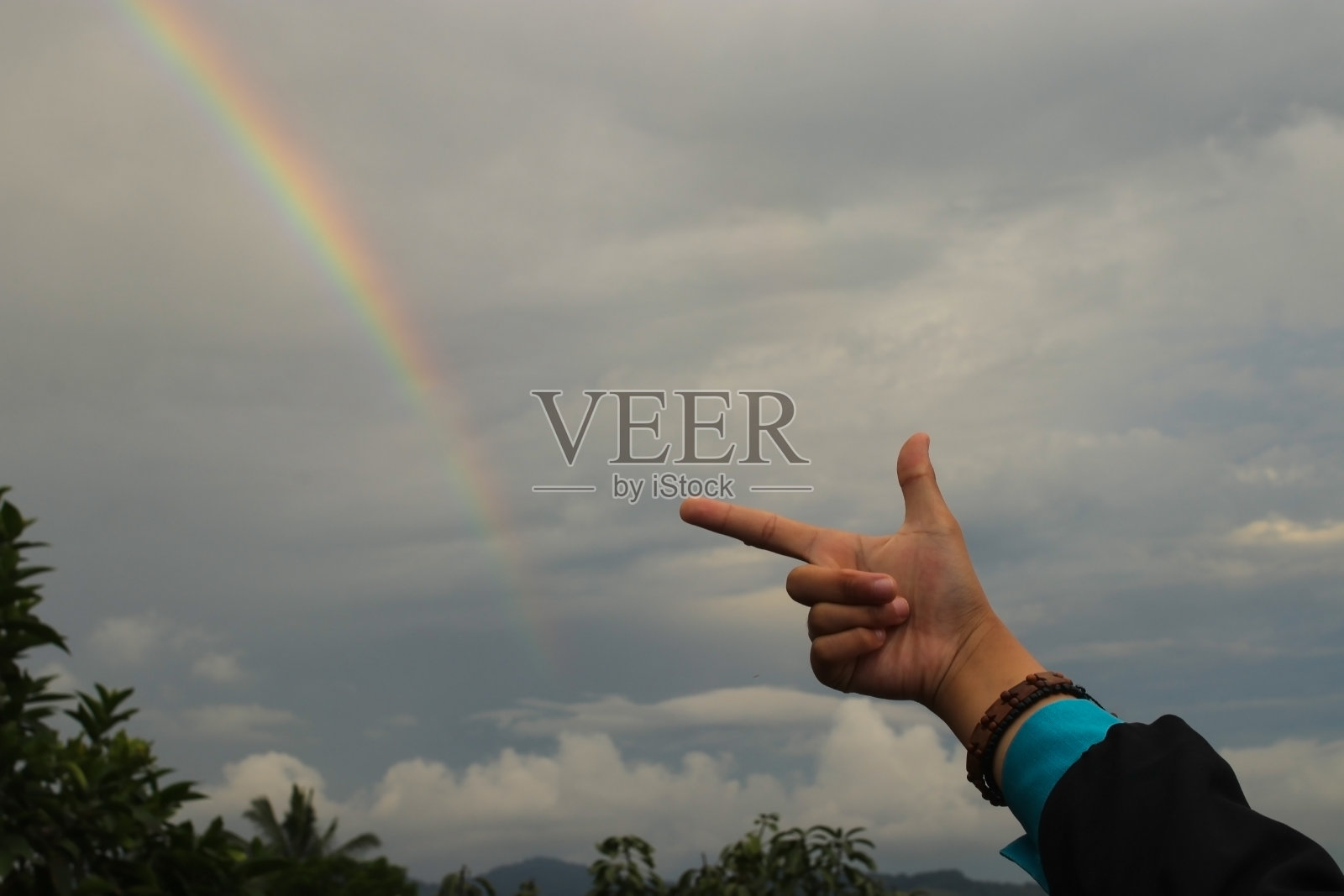 雨后阴天的傍晚，手指着彩虹照片摄影图片