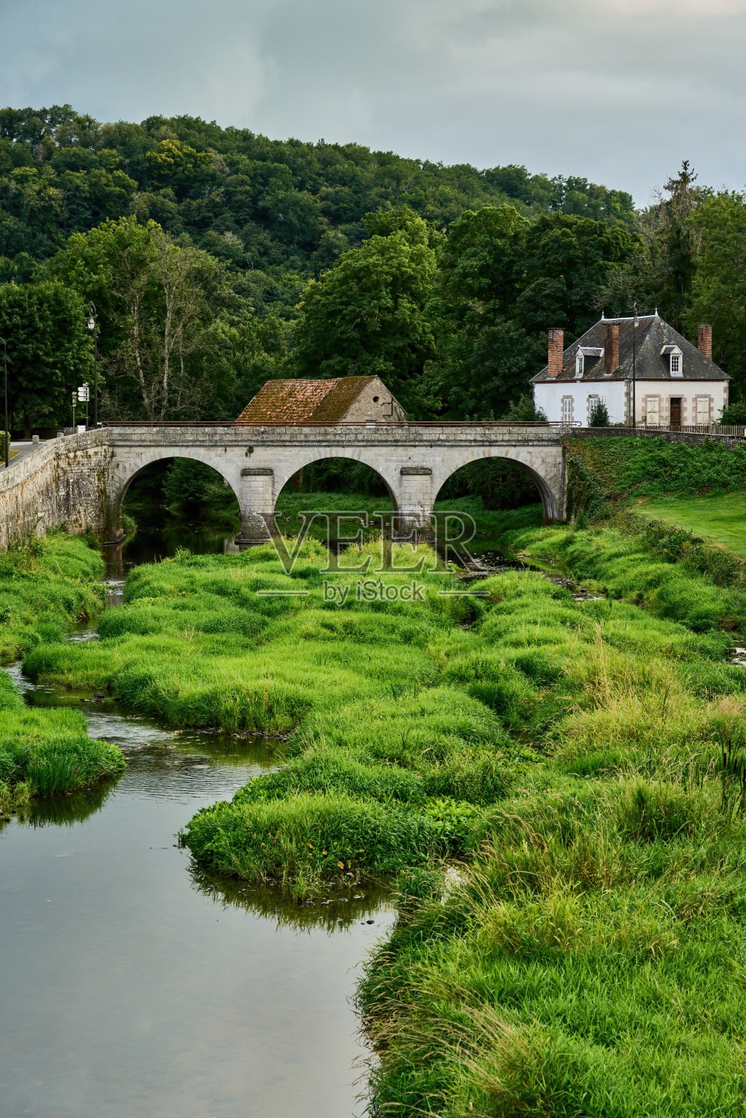 一座三拱的桥，桥上的小溪长满了绿草照片摄影图片