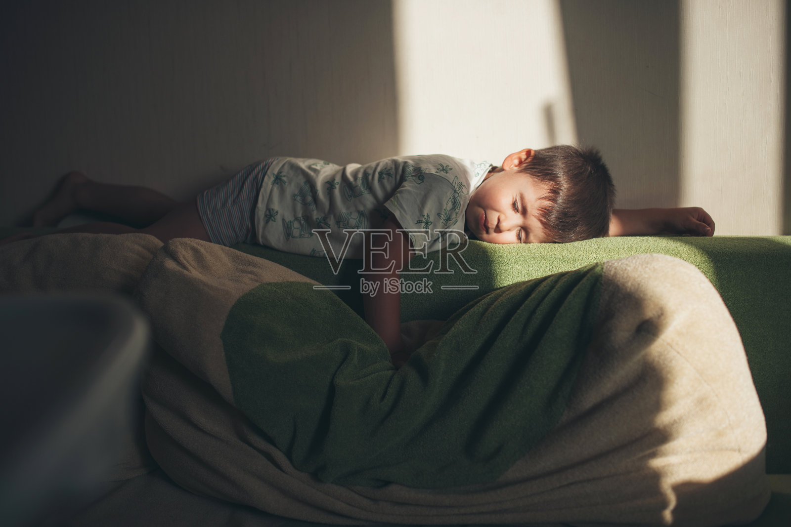 侧视图一个白人男孩在辛苦的一天后趴在沙发上睡觉，放松照片摄影图片