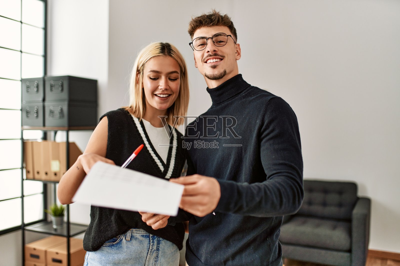 两名企业职员正在办公室里愉快地阅读文书。照片摄影图片