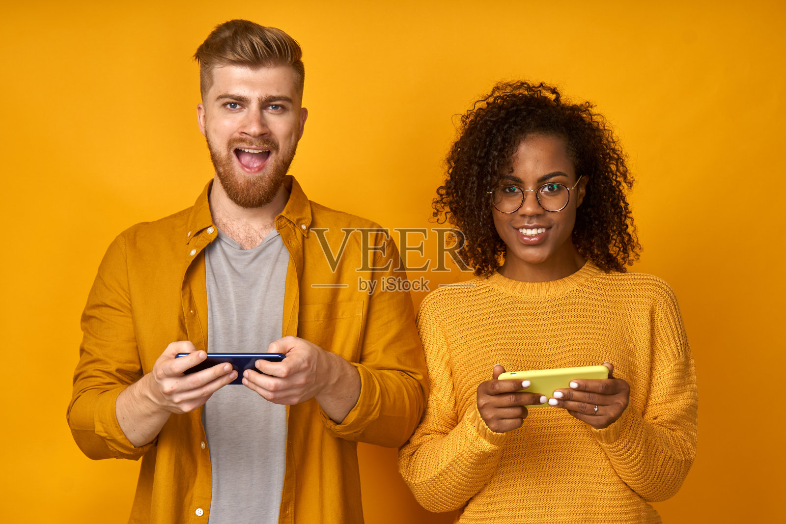 快乐快乐的非洲裔美国妇女和红发男子在智能手机上玩游戏，互相挑战，浏览网络，沉迷于现代科技。关系与技术概念照片摄影图片