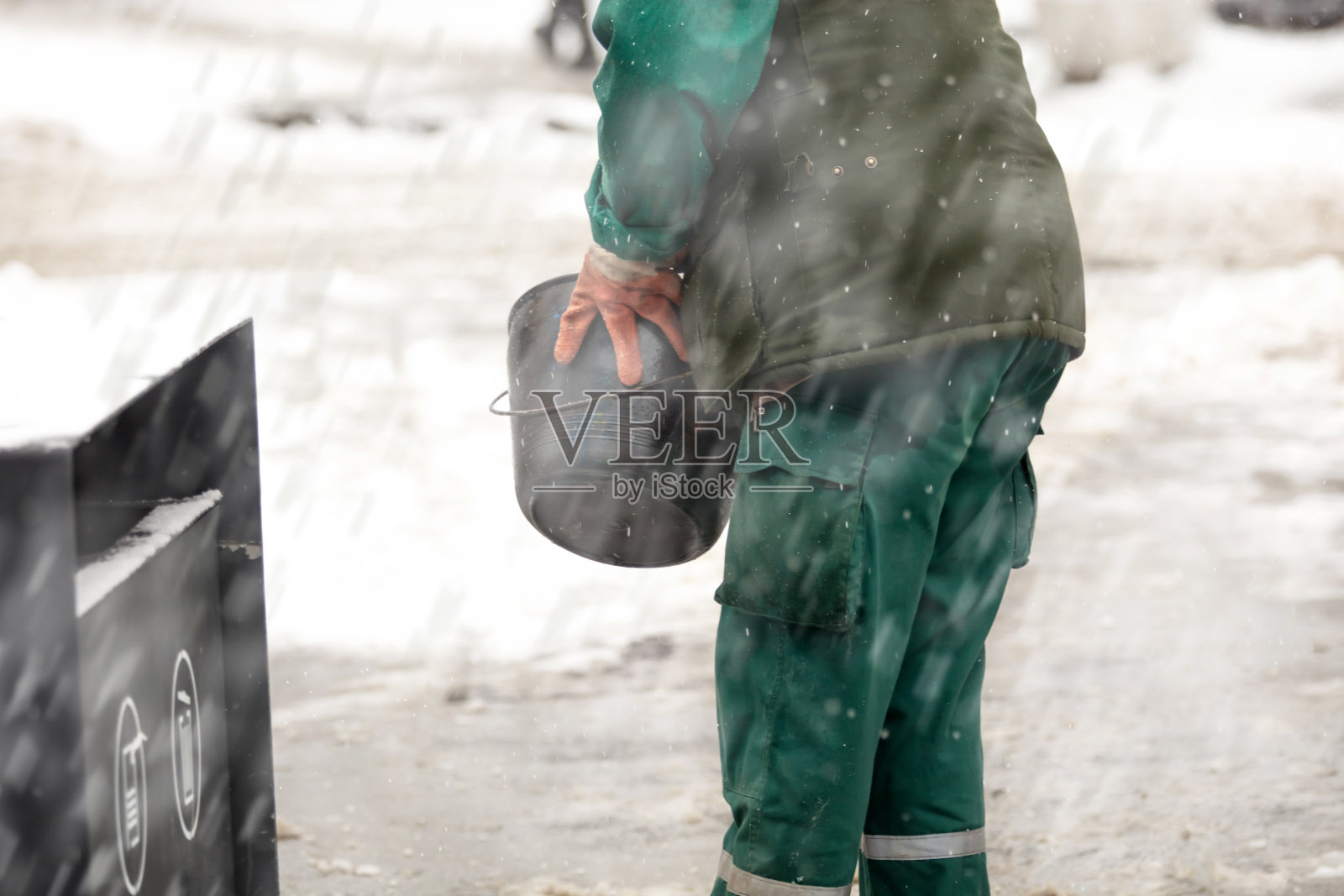 大雪期间，公共工作人员在结冰的人行道上撒盐。照片摄影图片