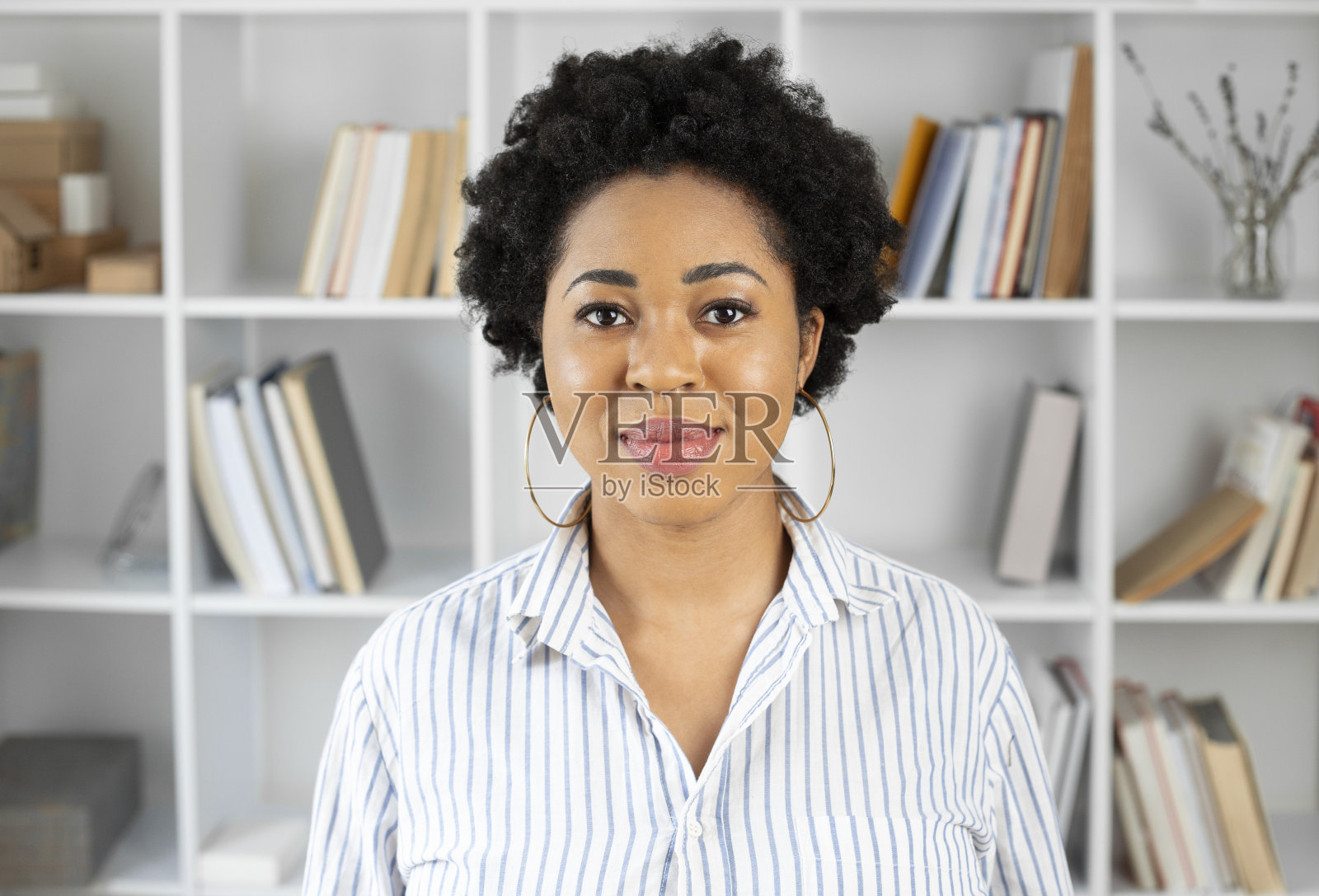 一个积极的非洲妇女的肖像在一个时尚的室内。黑人女学生的背景是书架上的书。照片摄影图片