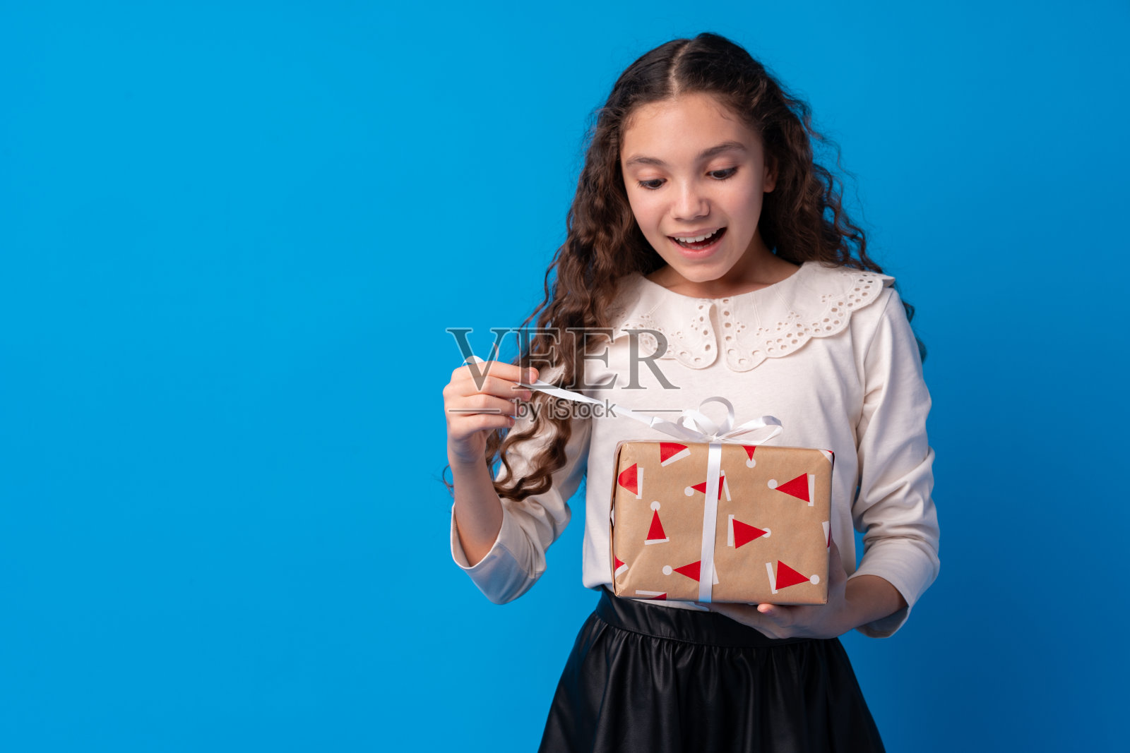 快乐的长发小女孩，拿着一个蓝色背景的礼品盒照片摄影图片